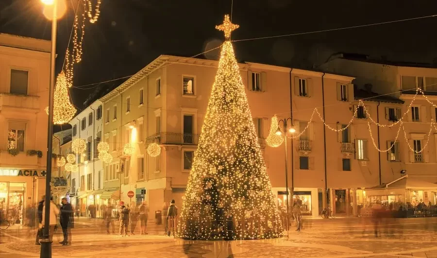 Albero di Natale illuminato in una piazza decorata di notte.