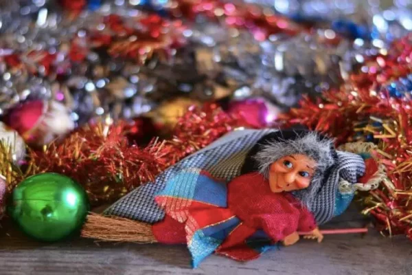 Befana su scopa tra decorazioni natalizie colorate.